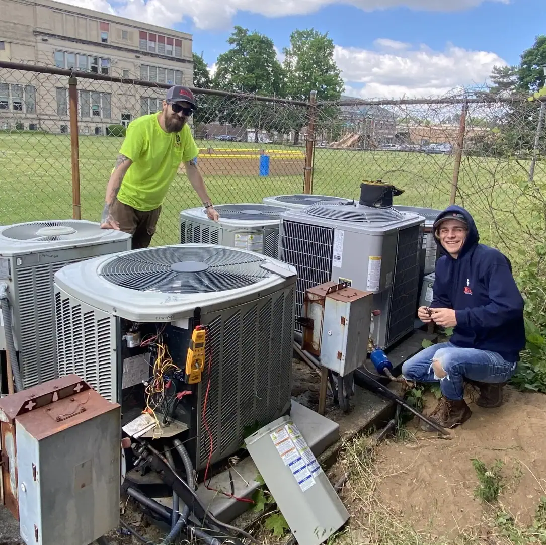 ENG Heating & Cooling technicians servicing commercial air conditioning units at a school building.