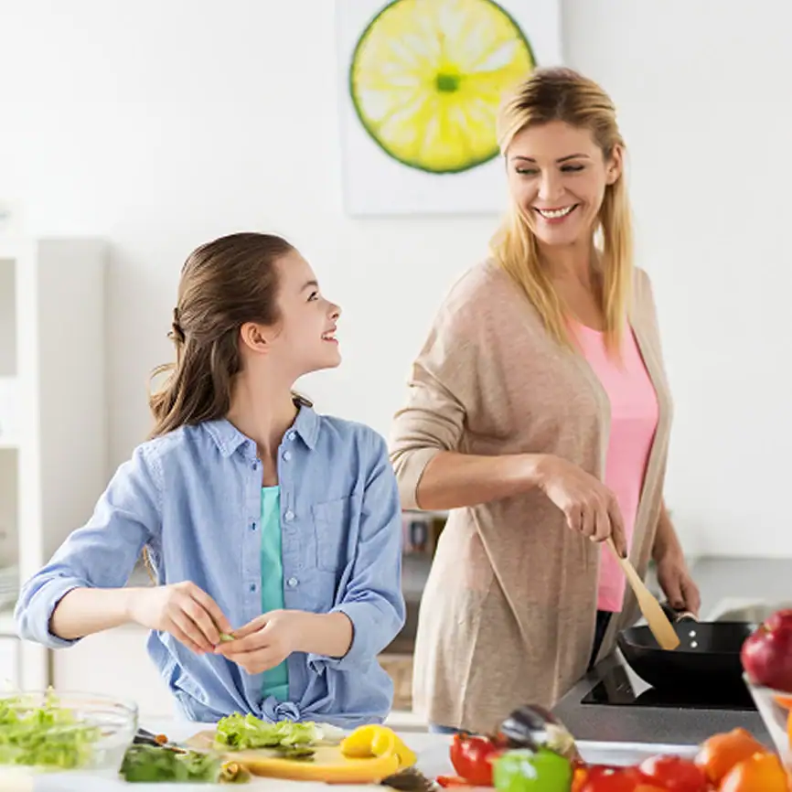 A mother and daughter cooking together in the kitchen.